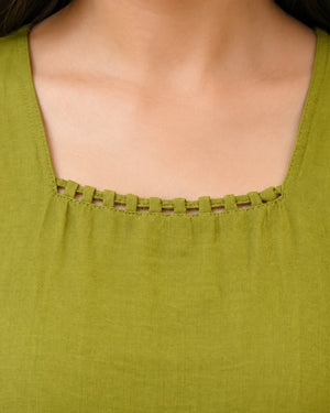 Close-up of a person wearing an olive green top, showing the neckline with decorative woven trim and a square cut.