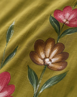 Close-up of olive green fabric with embroidered floral motifs, including a brown flower, pink blossoms, and green leaves.