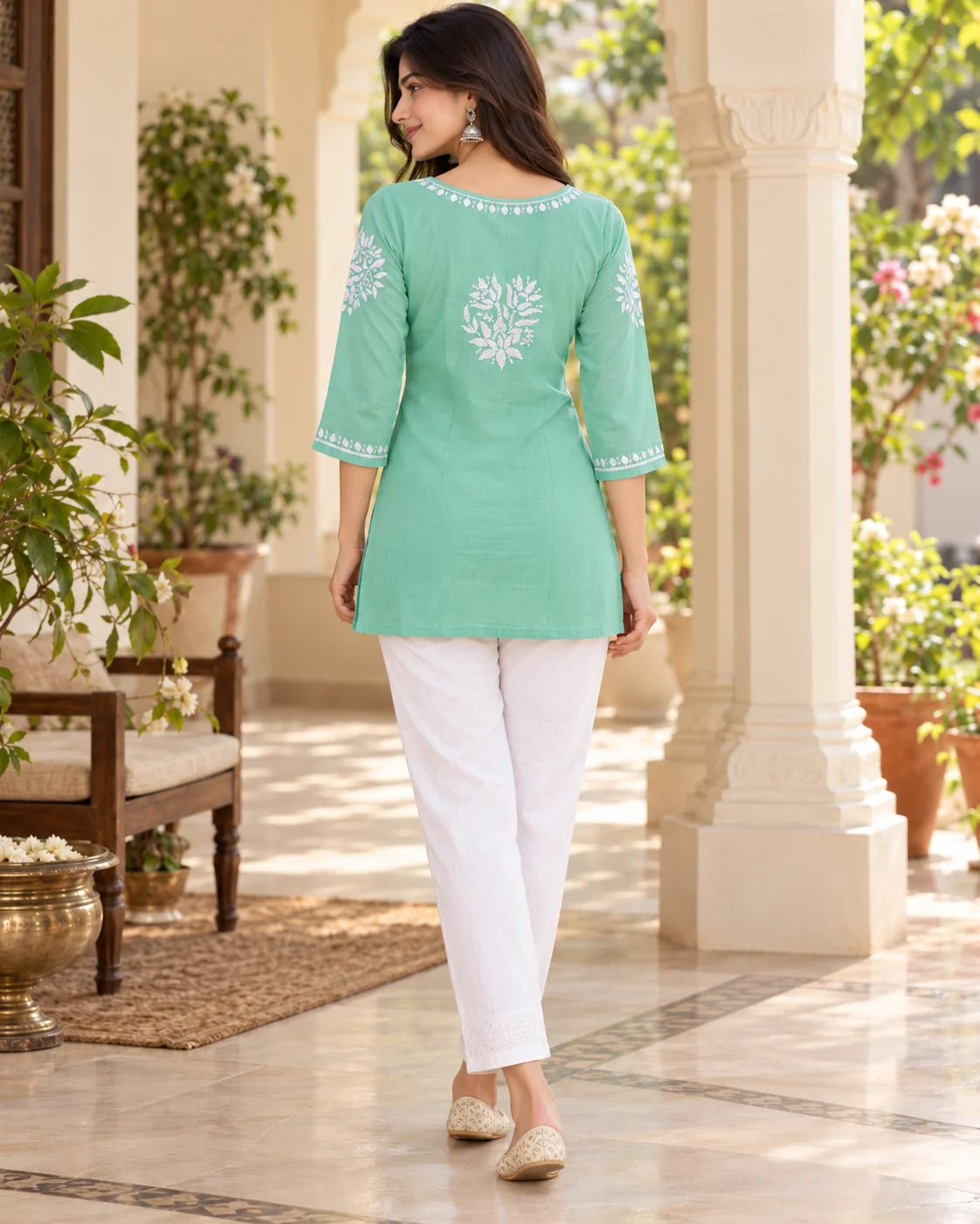 Back view of mint green chikankari short kurti showing white floral motif on the back, embroidered neckline and 3/4 sleeve borders