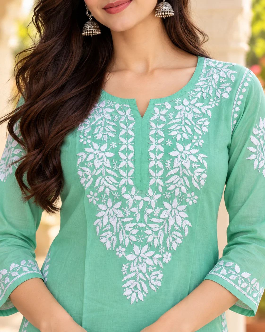 Close-up of the notched round neckline of a mint green chikankari kurti with intricate white leaf and floral hand embroidery