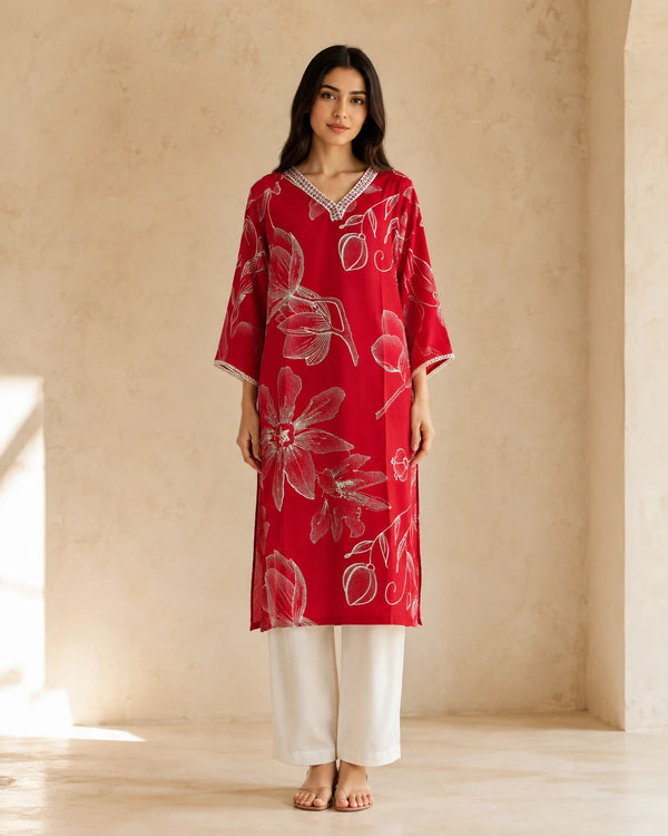 A woman stands in a warm, minimalist studio wearing a magenta rayon kurta with a white floral print.