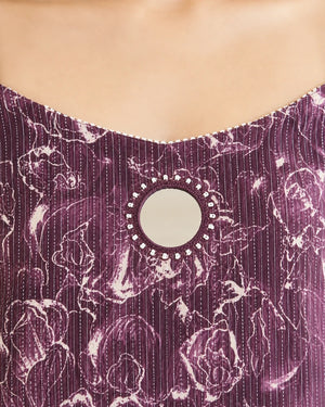 Close-up of a purple and white patterned top with a round mirror embellishment at the neckline.