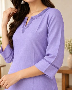 A woman wearing a lavender purple cotton kurta with a split V-neckline and embroidered trim details on the collar and cuffs.